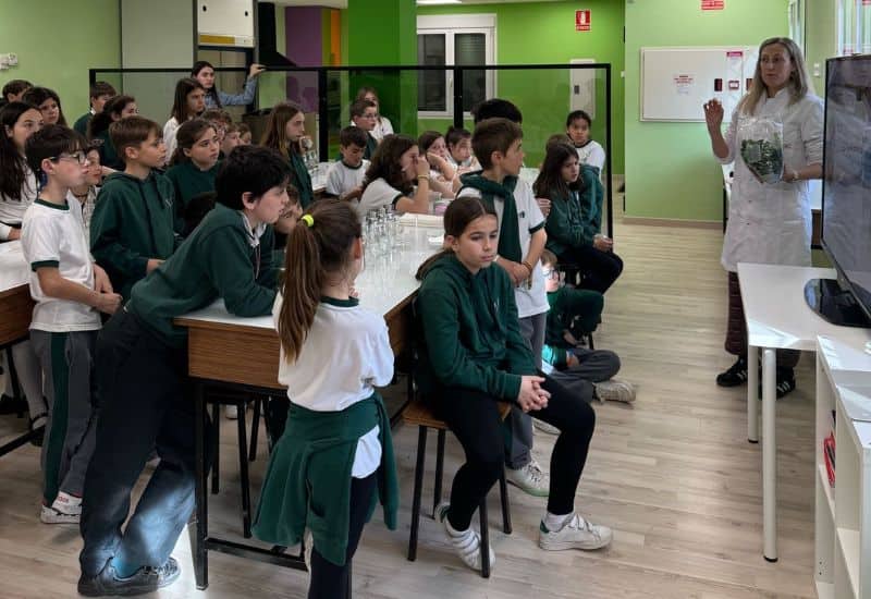 Alumnos de primaria saludando a cámara de forma animada durante su descanso en el patio del colegio en un ambiente de convivencia positiva.