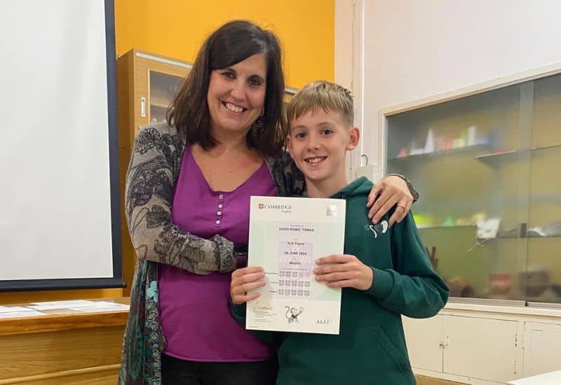 Docente de inglés apoyando a un alumno de Primaria durante una actividad lúdica para la certificación Starters de los Cambridge Young Learners.