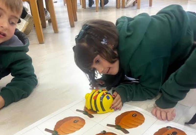 Alumna de Educación Infantil utilizando un robot de suelo para aprender secuenciación y orientación espacial de forma lúdica.