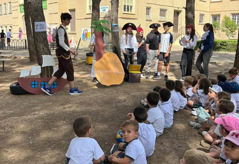 Alumnos realizando una dinámica de lectura teatralizada y dramatización lúdica al aire libre durante el recreo.